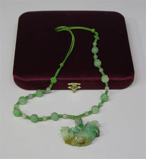 A Chinese carved jade pendant necklace, the pendant carved as an exotic ...