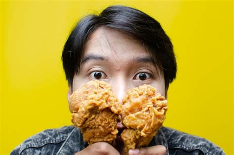 Premium Photo | Expressive asian man eats and smells fried chicken ...