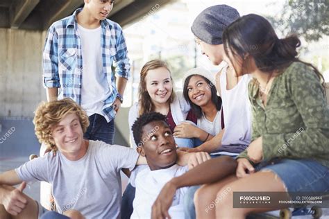 Teenage friends hanging out talking at skate park — togetherness, asian ...