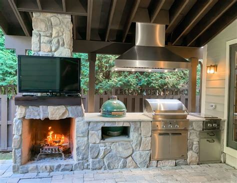 an outdoor kitchen with grill and television