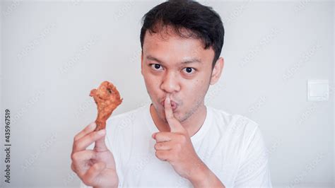 Young Asian man is eating fried chicken wear white shirt with silent ...