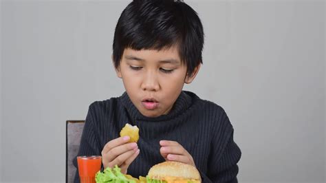 Cute Asian boy eating a delicious chicken nuggets with happiness ...