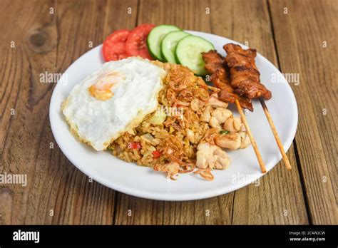 Nasi goreng fried rice chicken with egg tomato cucumber on white plate ...