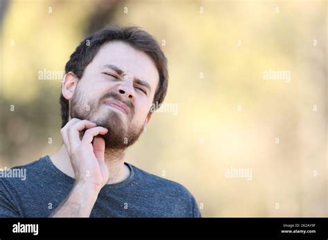 Man scratching itchy beard outdoors Stock Photo - Alamy