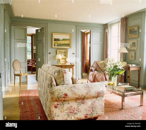 Floral sofa and glass-topped coffee table in pale grey-green French ...