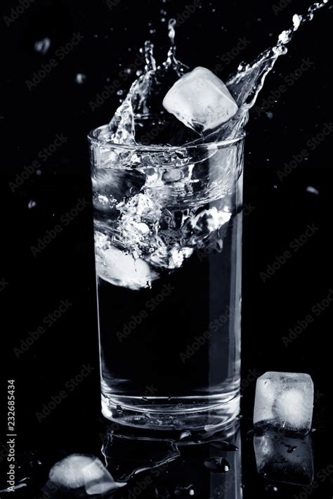 Water splash isolated. Water splash in glass with ice cubes and spilled ...