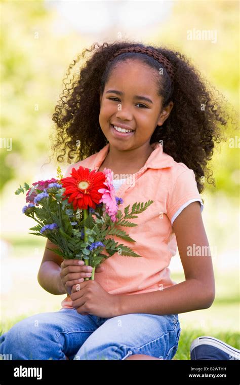 Young girl holding flowers and smiling Stock Photo - Alamy