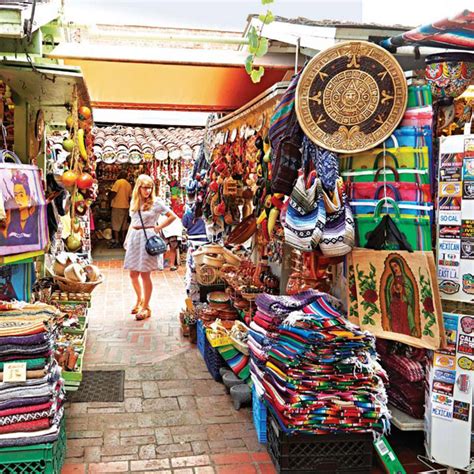 a woman walking through a market with lots of colorful fabrics and hats ...