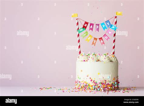 Birthday cake with brightly colored happy birthday banner Stock Photo ...