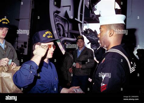 A petty officer checks identification of crew members coming aboard the ...