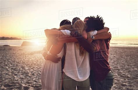 Young friends hugging in a huddle on sunset summer beach - Stock Photo ...