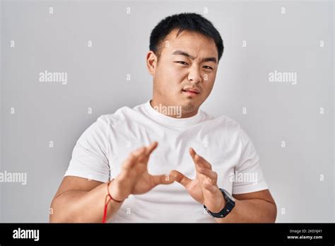 Young chinese man standing over white background disgusted expression ...