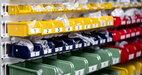 Hanging warehouse bins on a rail system with small parts and labels.