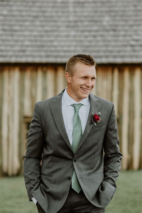 Groom styled with grey suit and sage green tie at a non-traditional ...