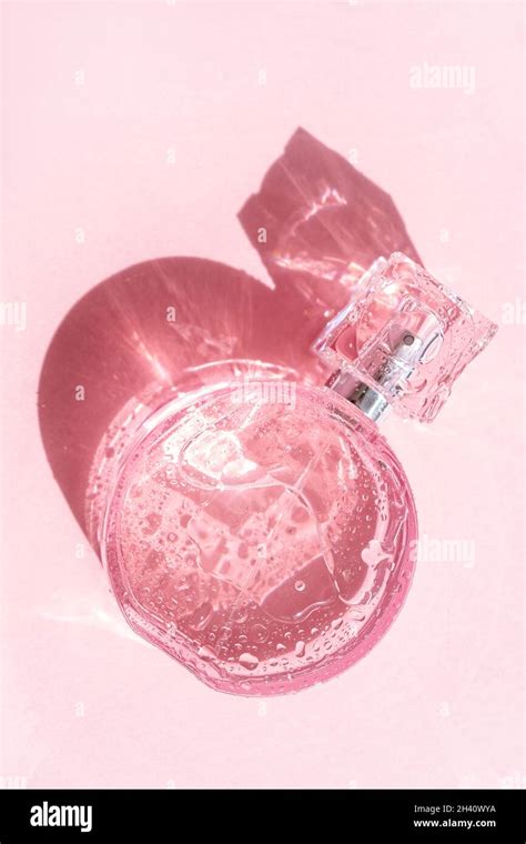 Transparent pink perfume bottle on pink background with strong shadow ...