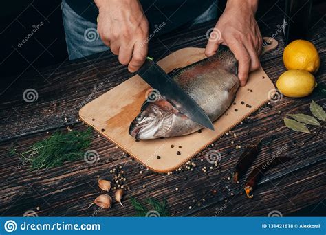 Male Chef Cuts Raw Trout on a Wooden Board in the Kitchen. Raw Fish for ...