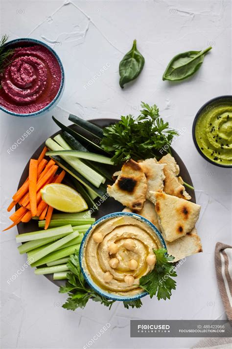 Various types of hummus served with fresh vegetables and pita bread ...