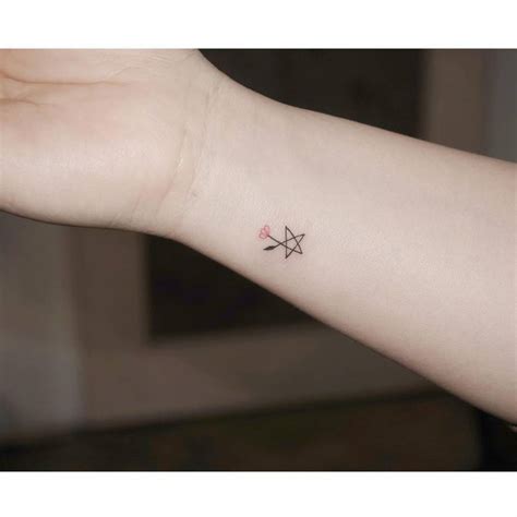 Minimalist star and flower tattoo on the wrist.