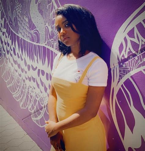 a woman standing in front of a purple and white wall with an angel ...