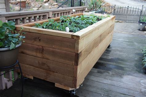 a wooden planter filled with lots of green plants on top of a wooden deck