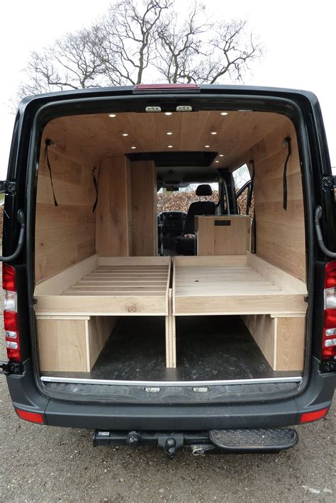 the back end of a van with two wooden benches in it's cargo area