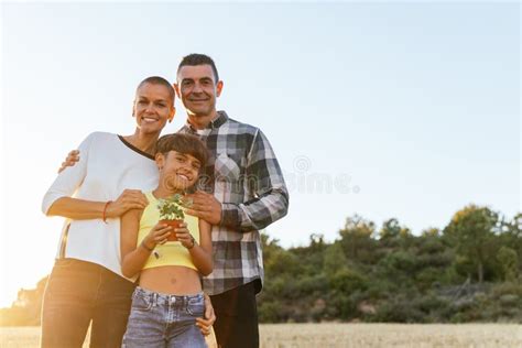 Family Smiling while Posing Outdoors in the Field with a Plant. Stock ...