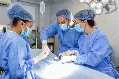 Surgeons operating below lighting equipment. Male and female doctors ...