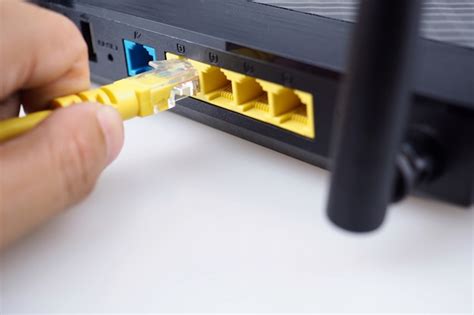 Hand connecting a yellow network cable on a lan port of a router ...