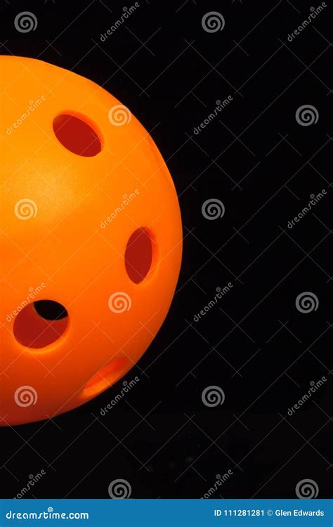 Orange Pickleball Emerging From Left On Black Background Stock Image