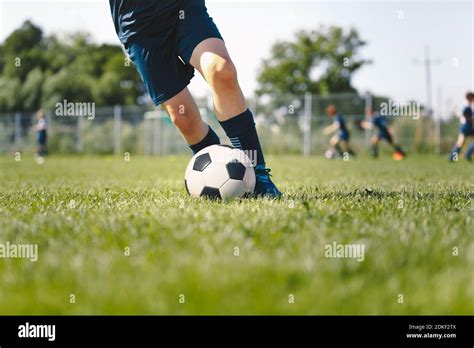 Junior Level Football Player Kicking Ball Legs Of Soccer Striker