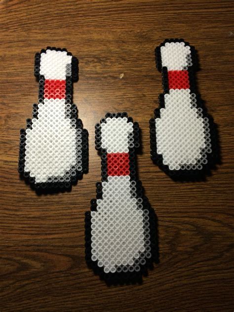 Three Pieces Of Art Made To Look Like Bowling Pins On A Wooden Table