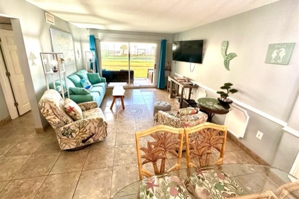 Living room with sliding patio door for easy access to beach, pool, & outdoor activities.