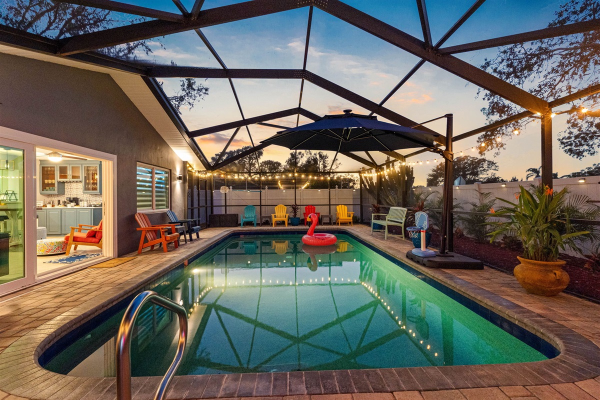 Soft outdoor lighting illuminates the patio and pool area, creating a cozy and inviting atmosphere for evening gatherings.