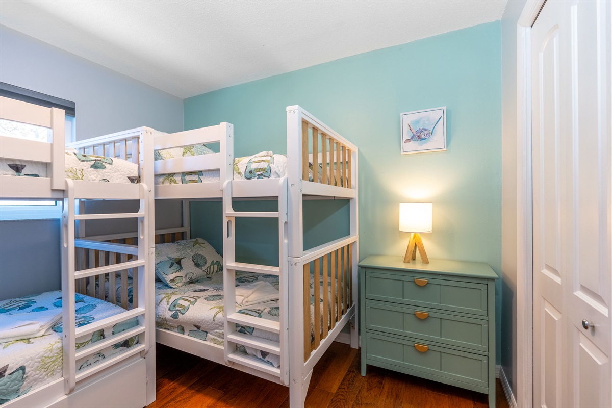 This playful and stylish bedroom is designed to accommodate families or groups, with ample space and a charming decor, wiith two sturdy bunk beds, offering a mix of white and light wood finishes.