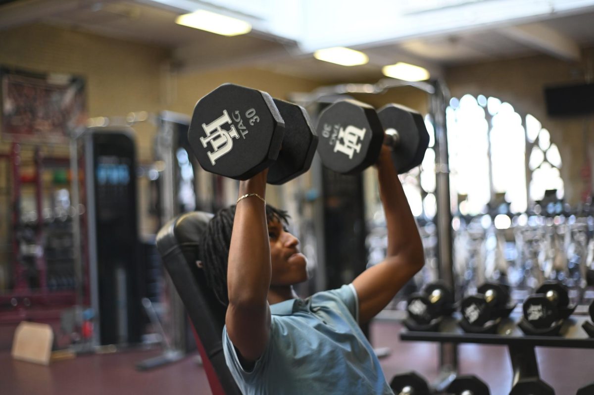 Senior Noah Runesha, the starting point guard for the varsity basketball team, lifts dumbbells in the fitness center to further prepare for the basketball season.