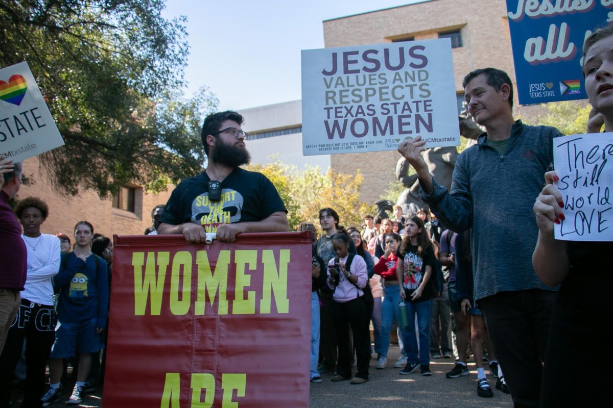 A member of The Official Street Preachers stares at counter protesters signs, Wednesday, Nov. 6, 2024, at the Fighting Stallions statue located on The Quad.