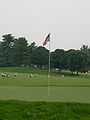 The pin on the 4th green at the Congressional Country Club during the Earl Woods Memorial Pro-Am prior to the 2007 AT&T National tournament. The usual yellow flags were replaced by American flags for the day, as the pro-am was held on Independence Day. Charles Howell III's group is in the fairway.