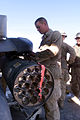 A Marine loads a rocket pod onto an AH-1W Super Cobra