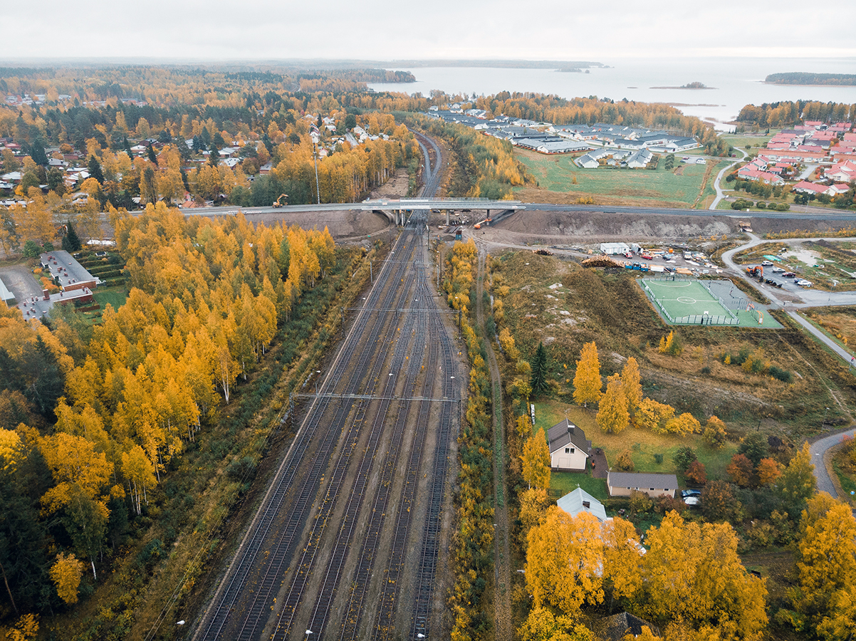 An aerial view of a train station: a lake and urban settlement can be seen in the background.