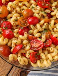 a close up shot of red and orange tomato halves nestled in cavatappi pasta