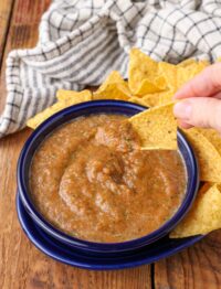 a vertically aligned close up photo of a chip that has been dipped in this easy salsa