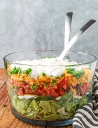 salad in clear bowl with dressing on top with tongs in bowl