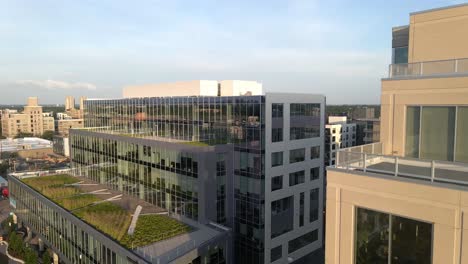 aerial-view-of-a-couple-of-buildings-during-golden-hour,-camera-approaching-to-a-7-floor-hight-building