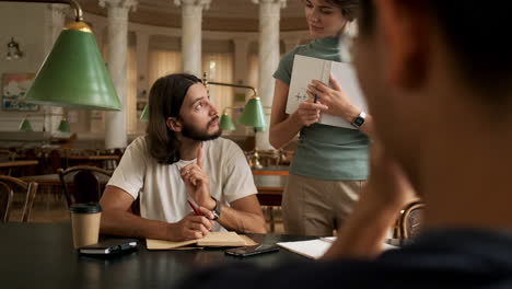 Young-student-studying-with-tutor-in-library