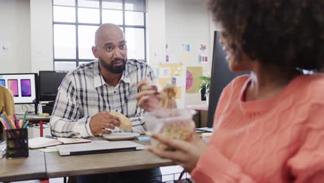 Two-happy-diverse-creative-colleagues-in-discussion-during-lunch-in-casual-office,-slow-motion