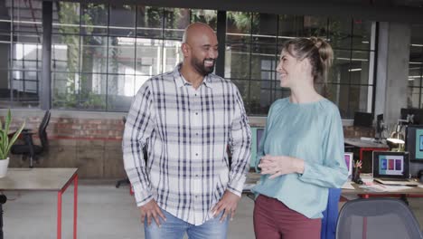 Two-happy-diverse-creative-designers-in-discussion-in-casual-office,-slow-motion