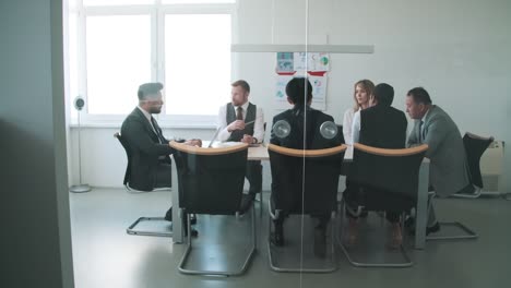 Group-Of-Business-People-Discussing-Together-At-The-Table-During-Business-Meeting-At-Office