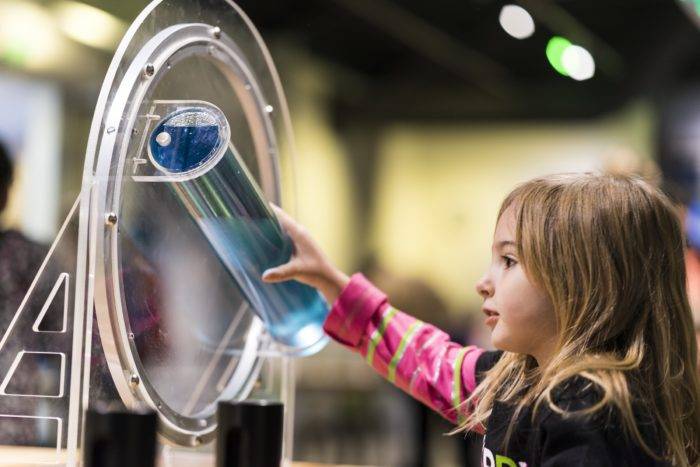 little girl playing with science exhibit