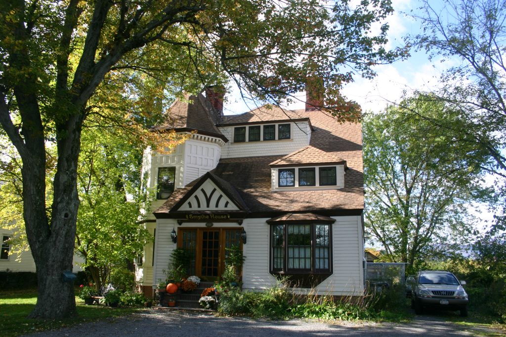 three story white house with brown roof