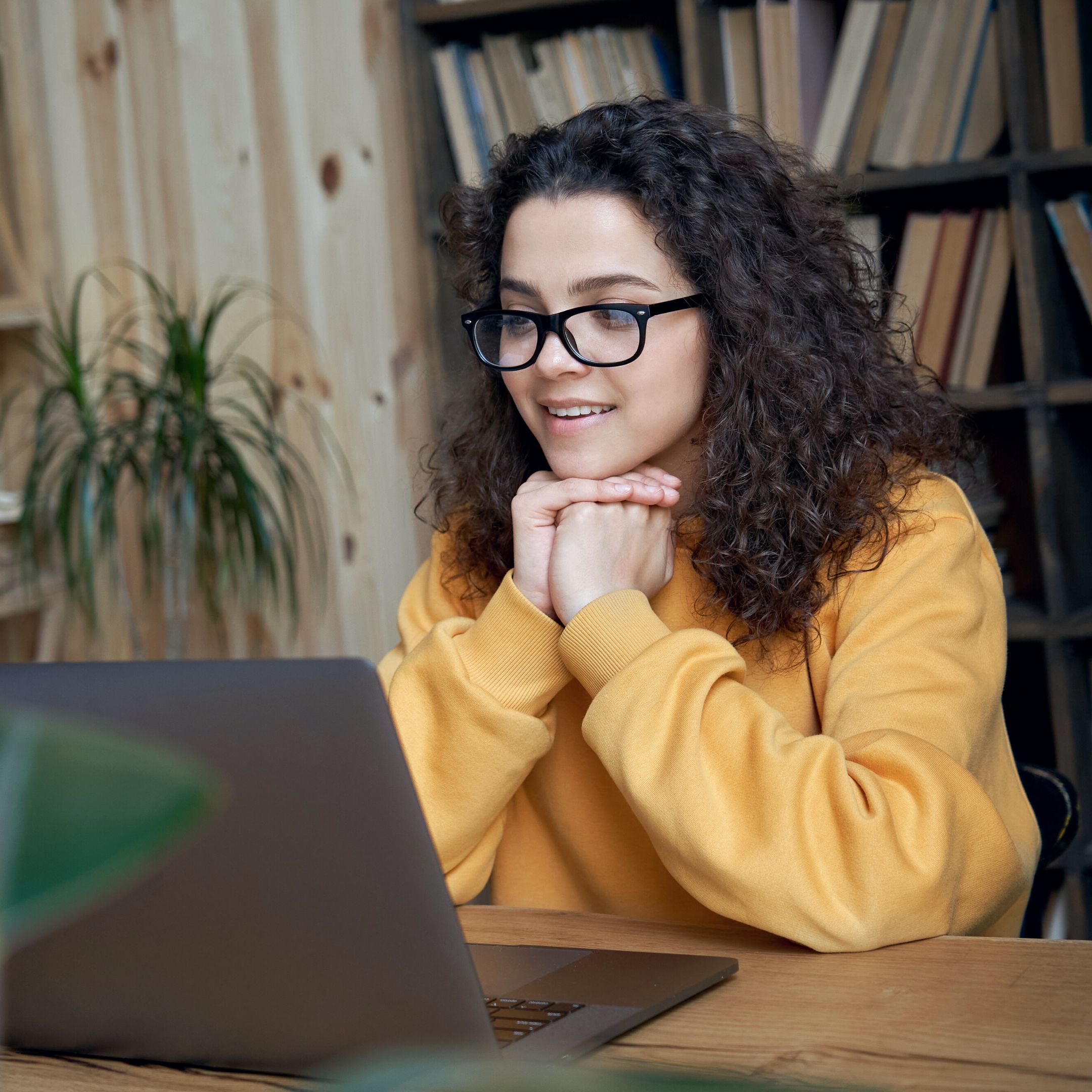 Young woman rests her head on clasped hands while she looks at a computer screen. All Vermont women can participate in VWW's Career Mentor Network.